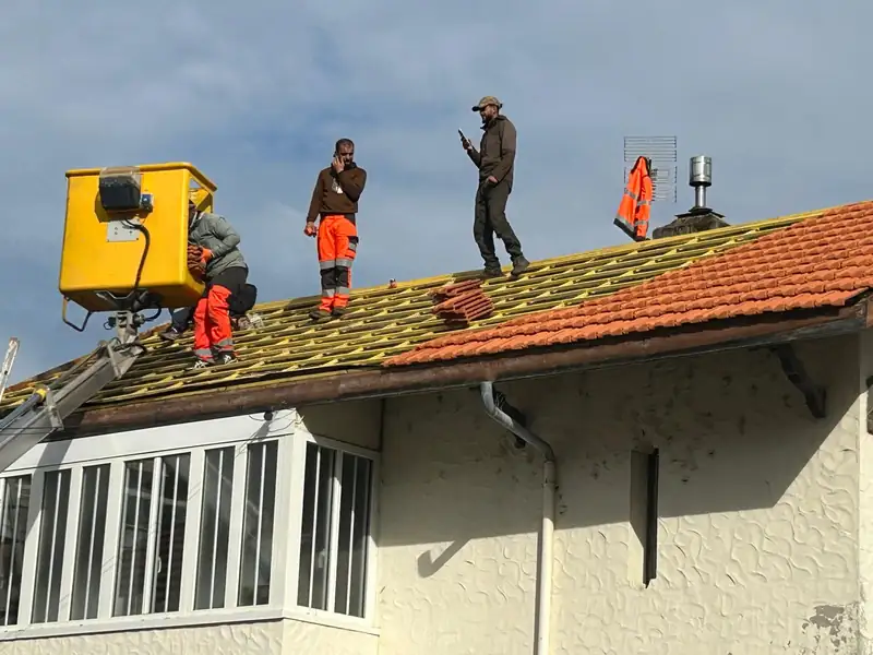 Équipe de couvreurs en nacelle pendant la rénovation d’une toiture en tuiles